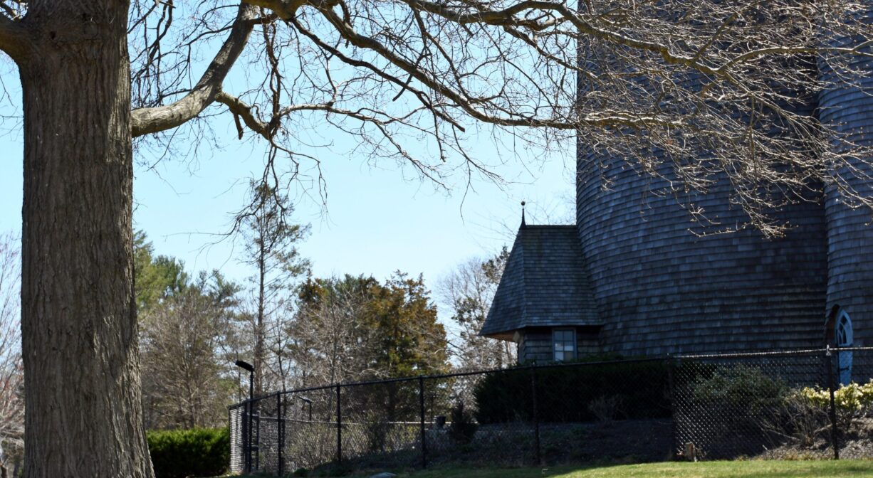 An ornate tower on a lawn with some trees.