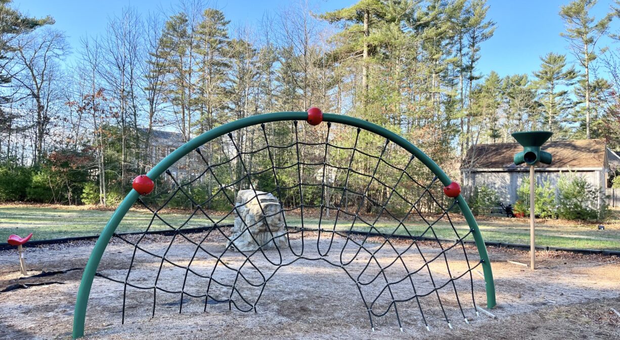 A photograph of a green and red climbing structure within a playground.