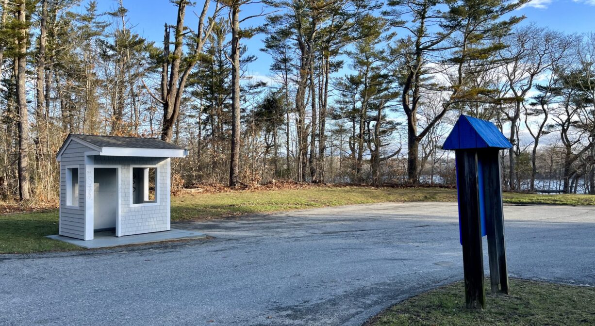 A photograph of a guard station and a property sign on a driveway.