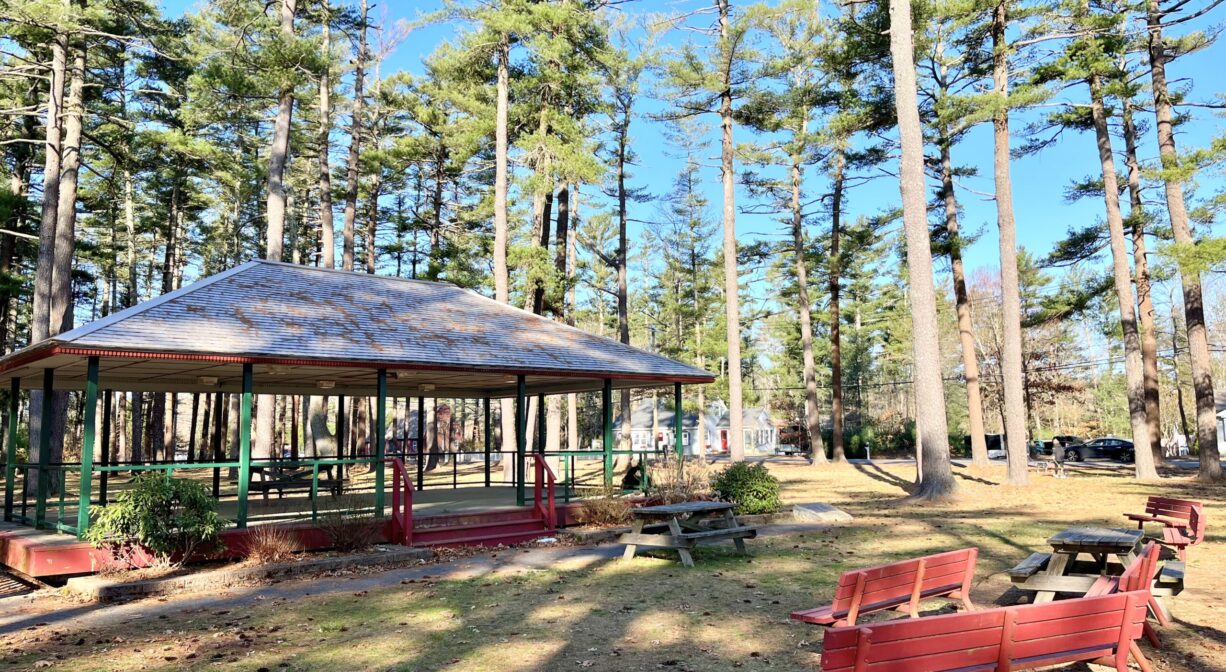 A photograph of a red picnic pavilion with red benches in the foreground.