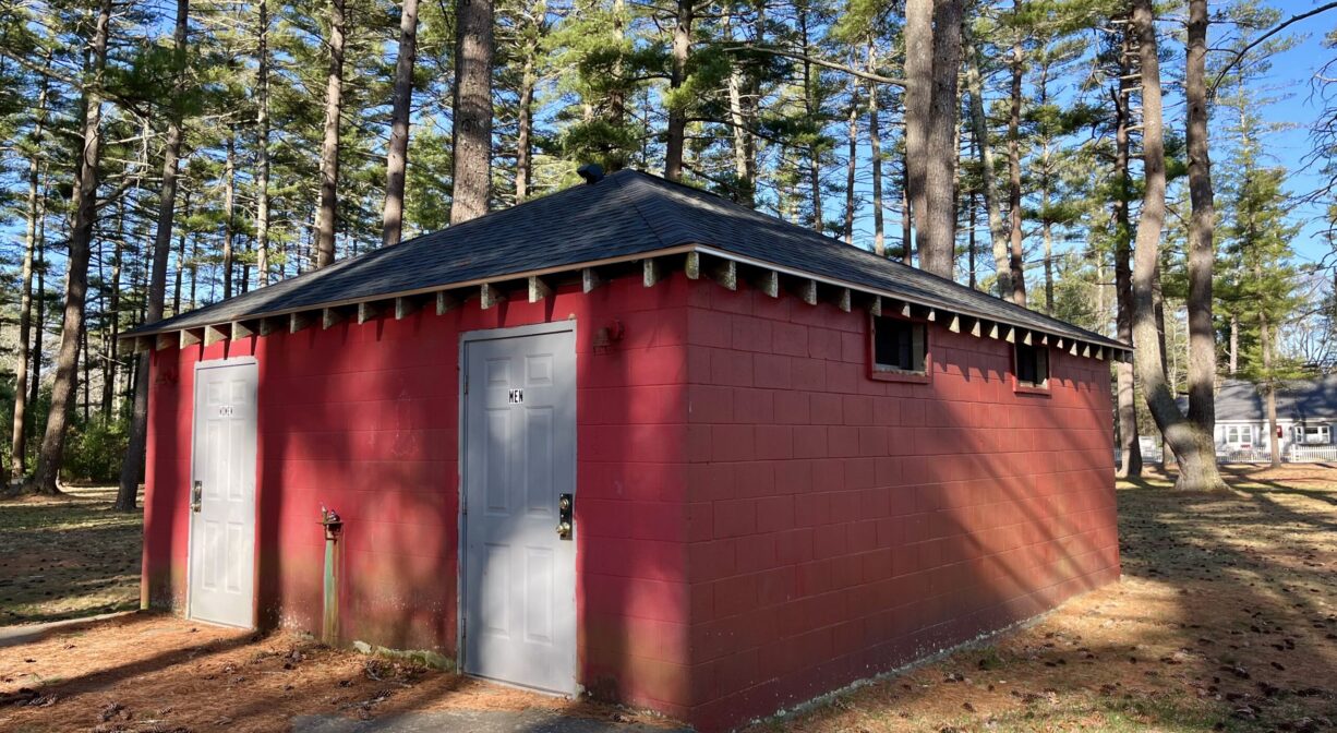 A photograph of a red storage shed, with trees in the background.