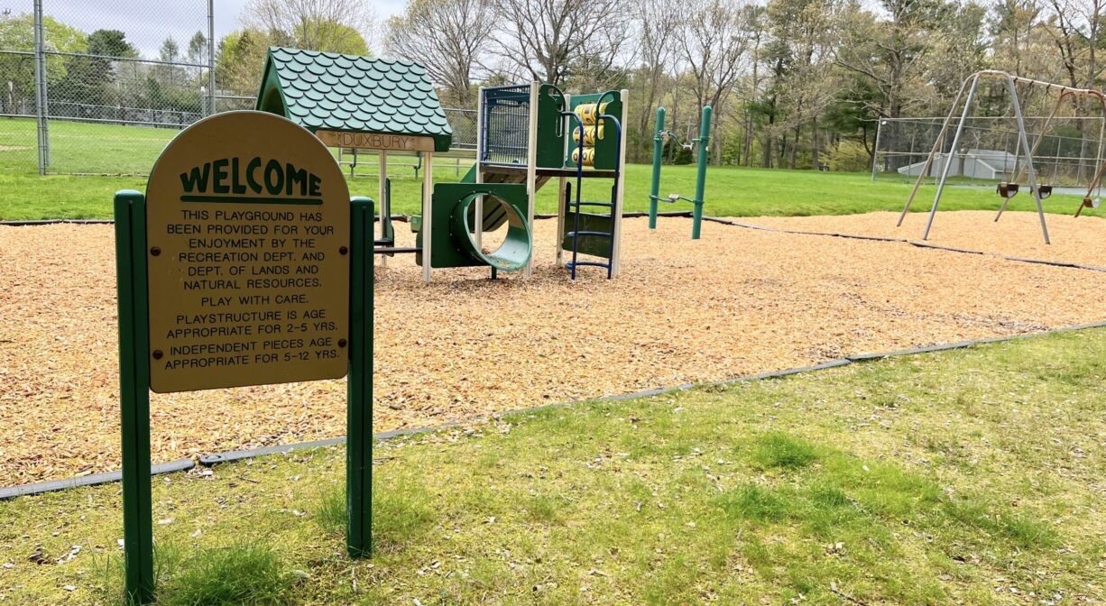 A photograph of a playground and a property sign.