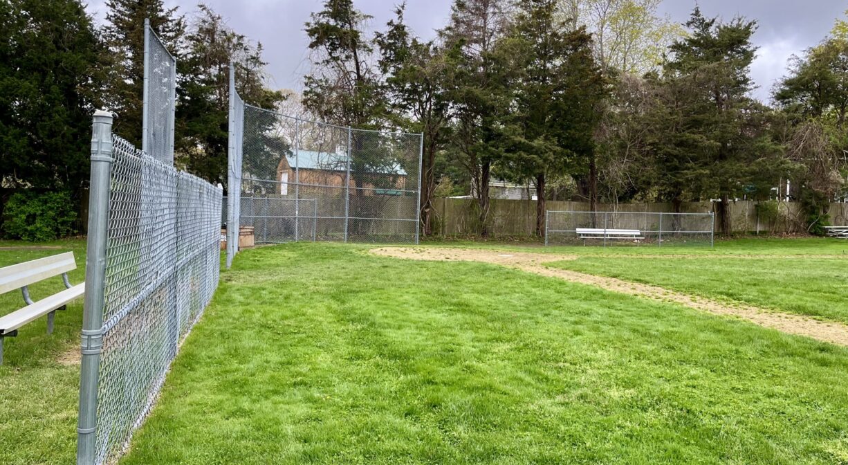 A photograph of a baseball field with trees in the background.