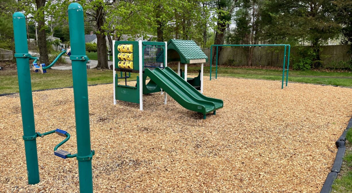 A photograph of a toddler playground with woodchips as its surface.